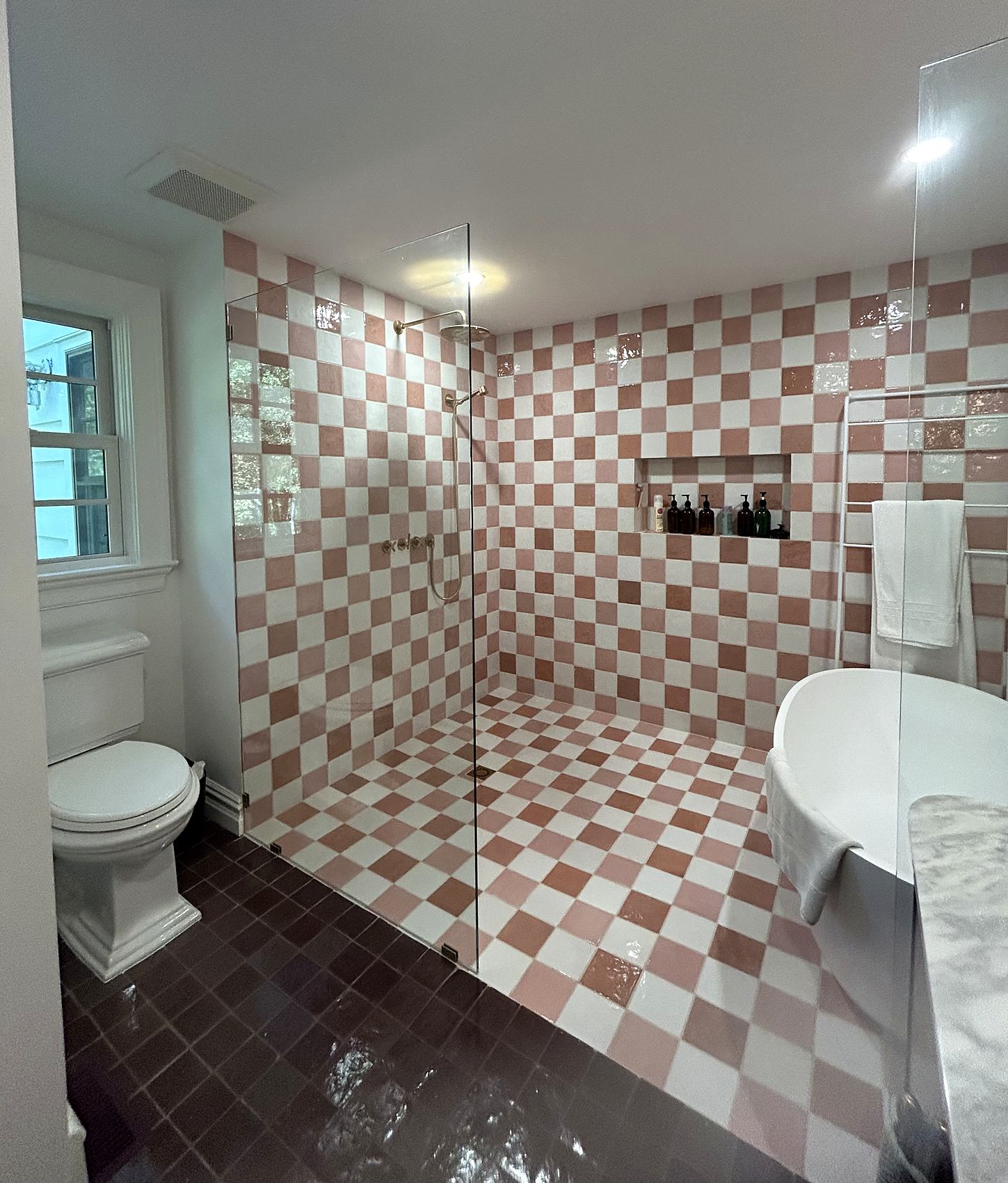 Bathroom with pink and white checkered tile, a walk-in shower, and a freestanding tub