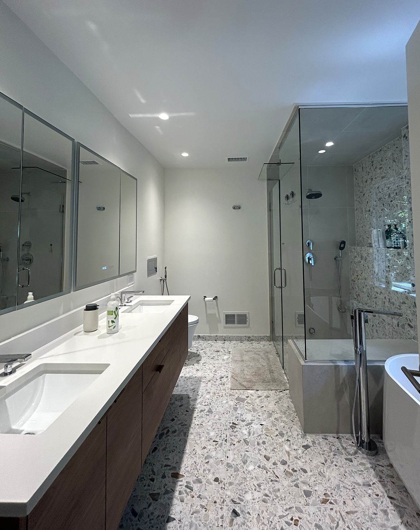 Bathroom with a long double vanity, terrazzo floor, and glass shower