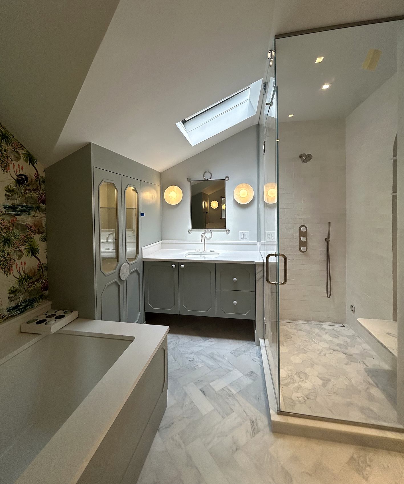 Primary bathroom with sage cabinetry, a skylight, and a glass shower