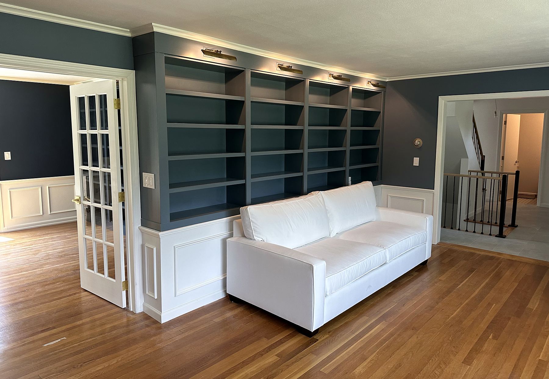 Blue built-in bookcases with picture lights above white wainscoting