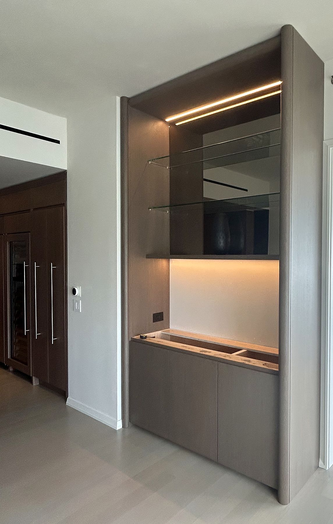 Built-in wood cabinet with lit glass shelves