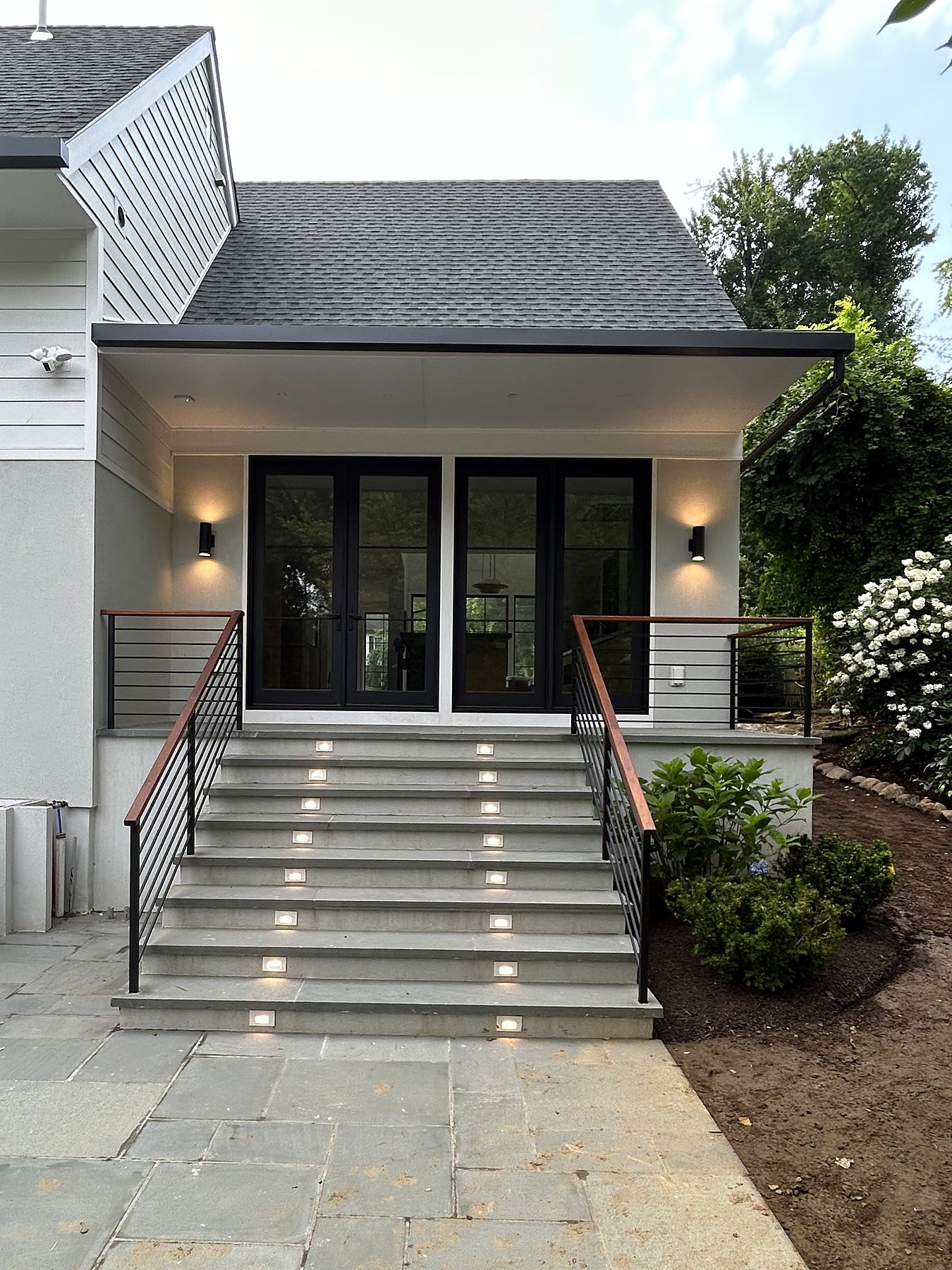 Covered entry with black French doors and lit stone stairs
