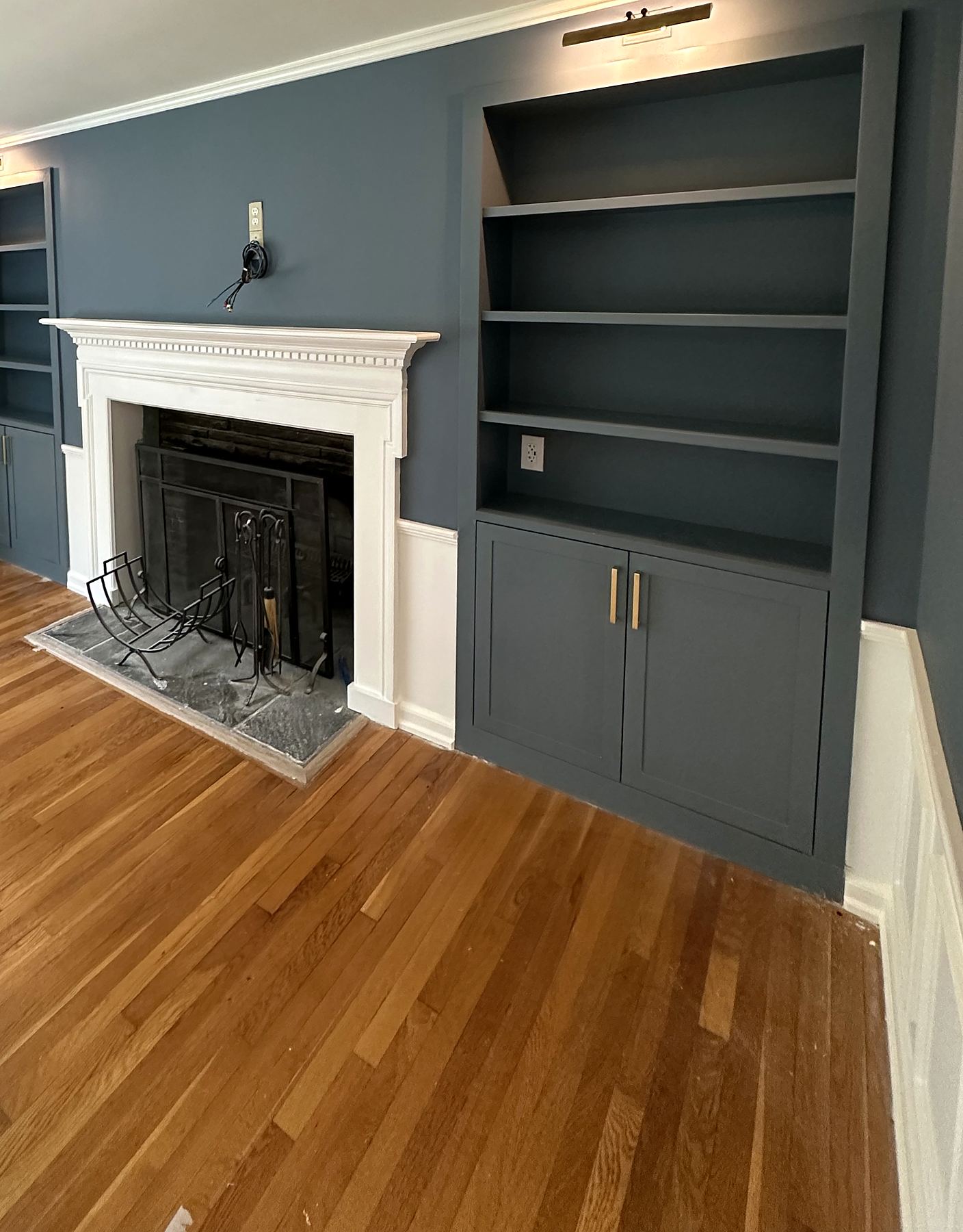 Fireplace with a white mantel beside blue built-in shelving and cabinets