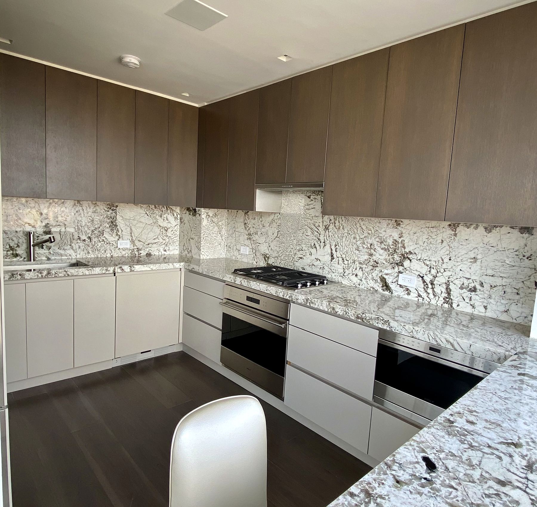 Kitchen with wood upper cabinets, white lowers, and stone counters and backsplash
