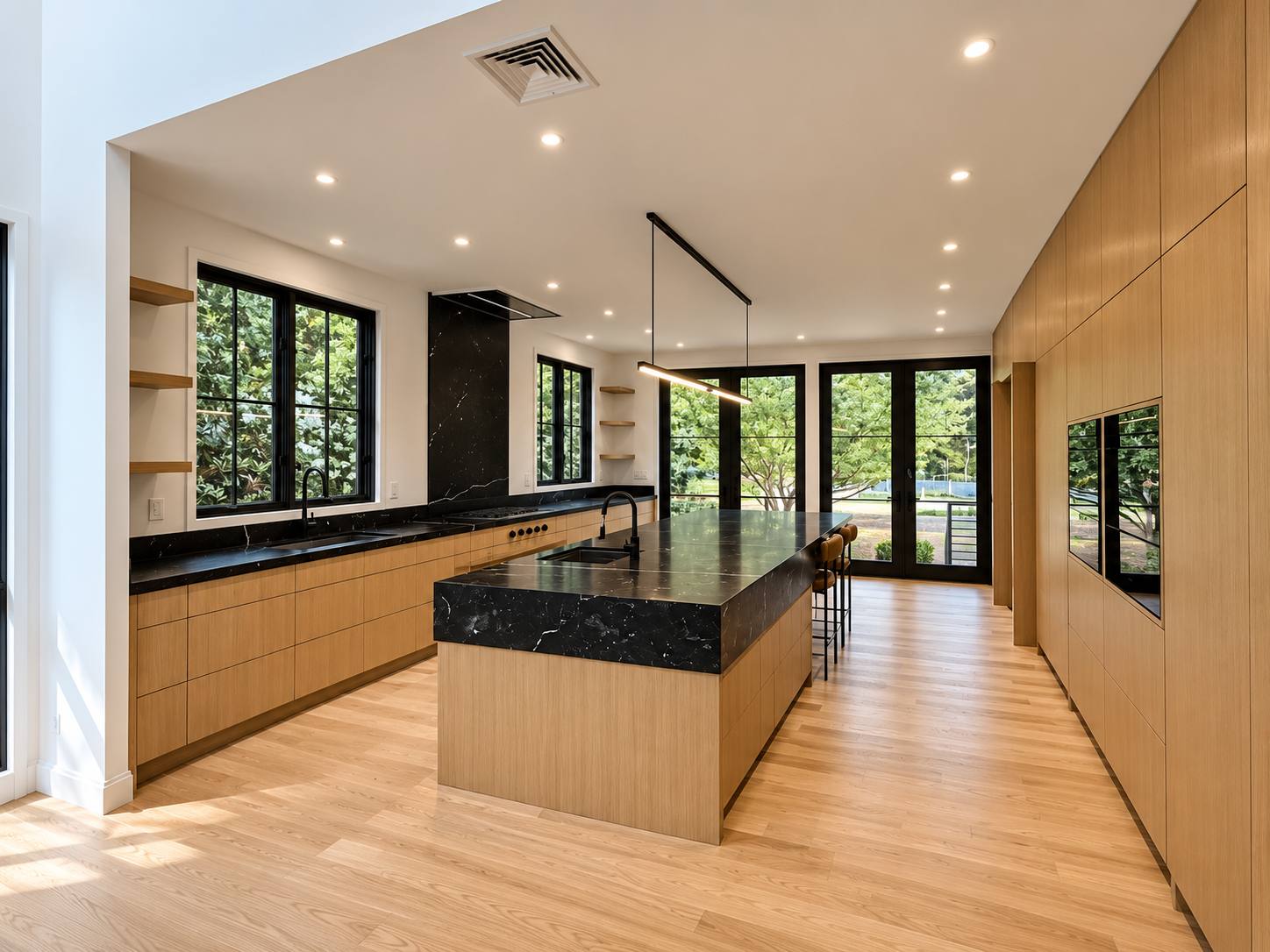 Kitchen with oak cabinetry, black stone island, and black-framed windows