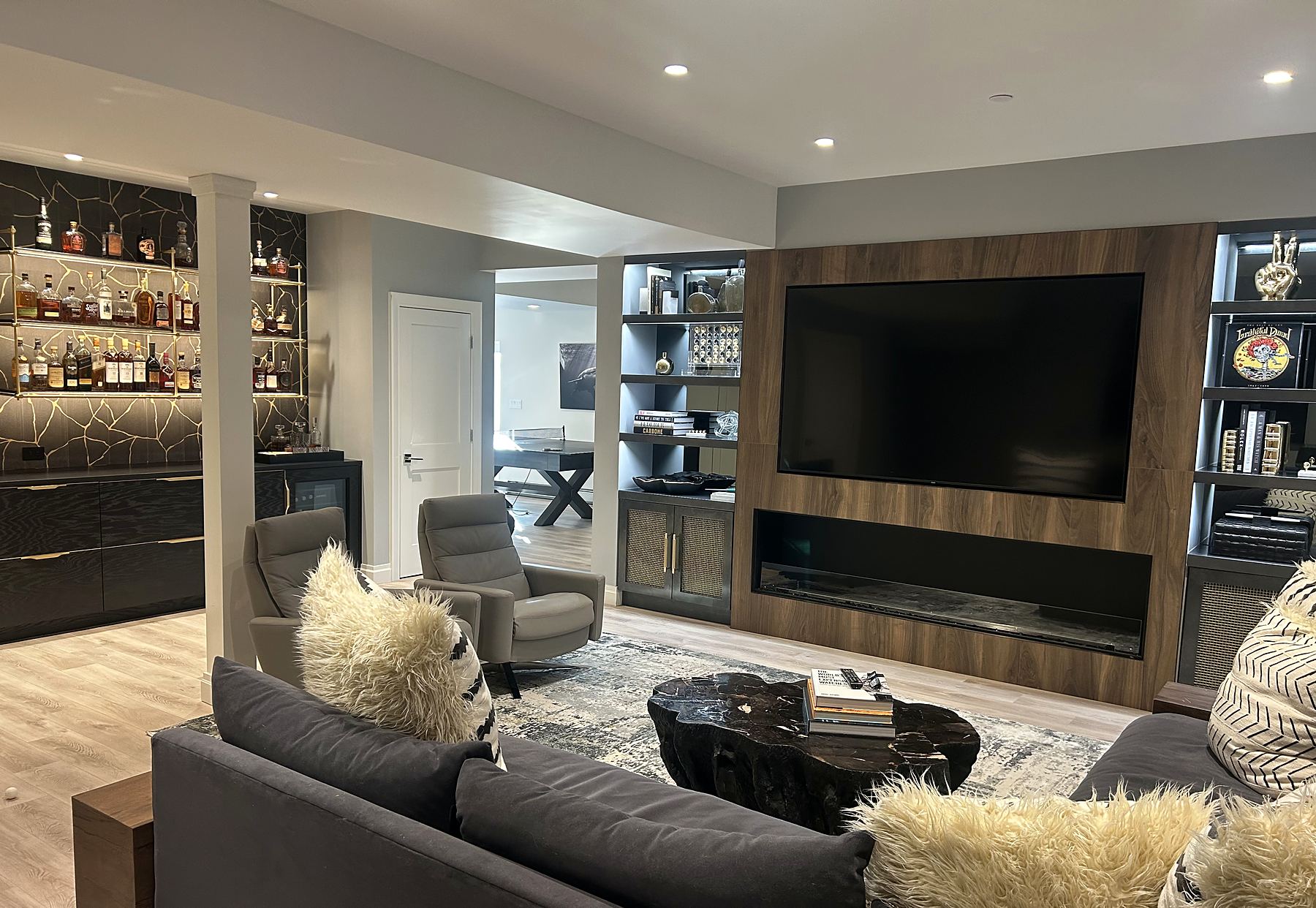 Lounge with a walnut media wall, fireplace, and a lit bar