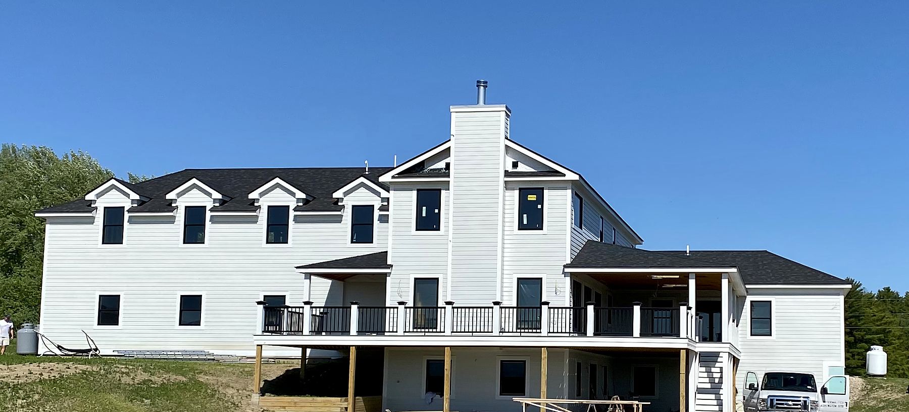 Large white new-build house with a wraparound deck